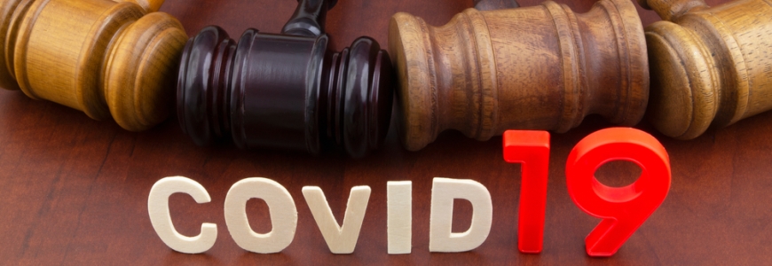 Four gavels lying next to each other on a wooden table with COVID 19 in front