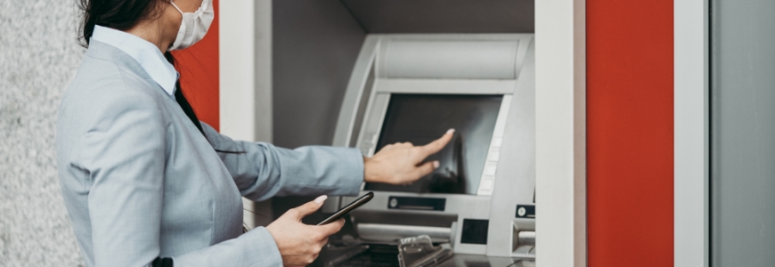 A business woman at an ATM wearing a mask