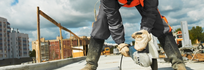 Construction site with a man holding a grinder and cutting concrete