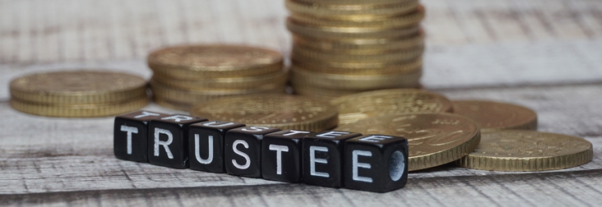 Dice with the name trustee written across in front of gold coins