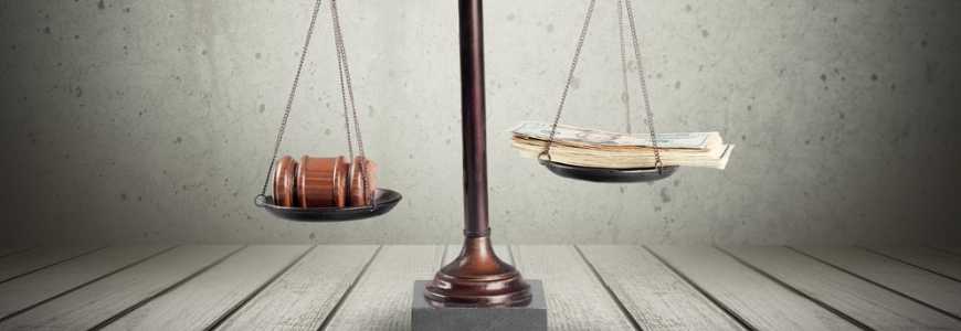 Scales of justice with gavel on one side and a pile of cash notes on the other side