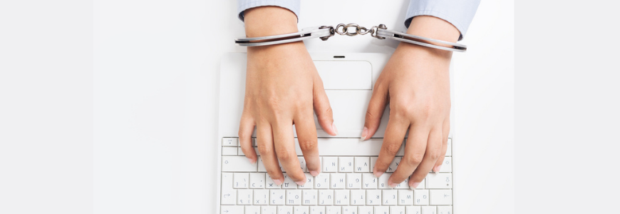 Female hands in handcuffs with laptop