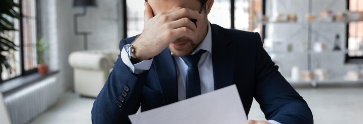 Unhappy businessman feeling stressed about bad news on a piece of paper.