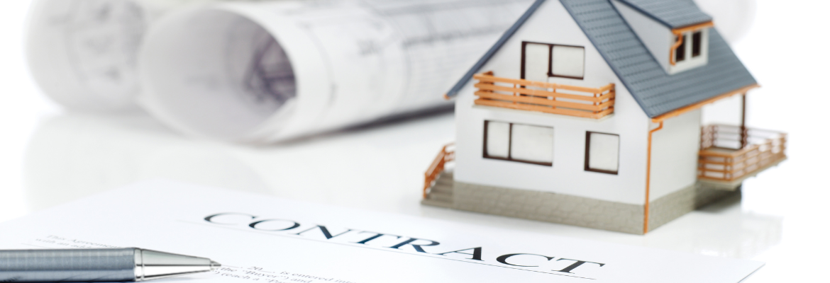 A contract and pen placed beside architect drawings and a house model